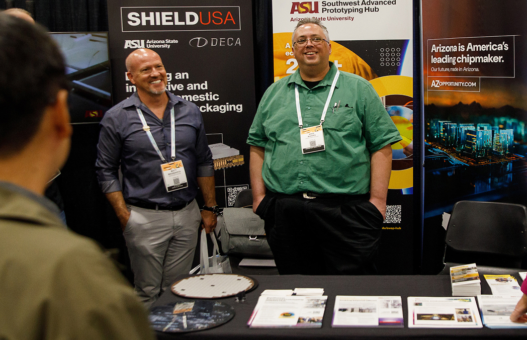 Two presenters stand in front of ASU's booth at SEMICON West 2025